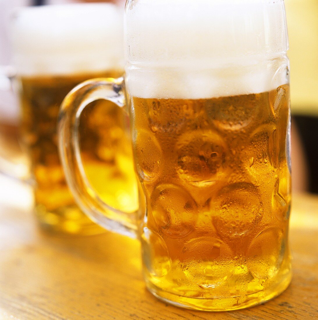 Two tankards of cold beer on a wooden table