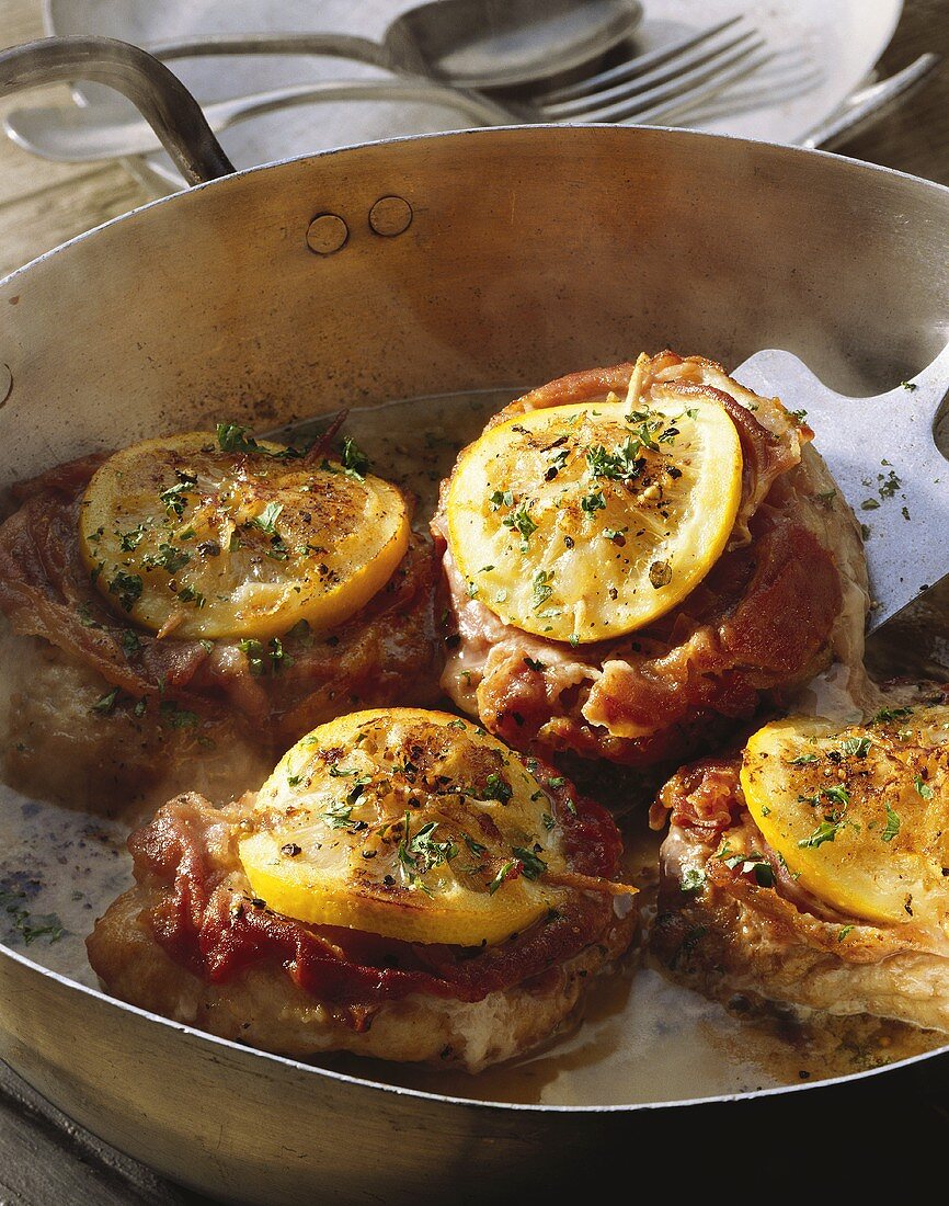 Pork medallions with ham and lemon in frying pan