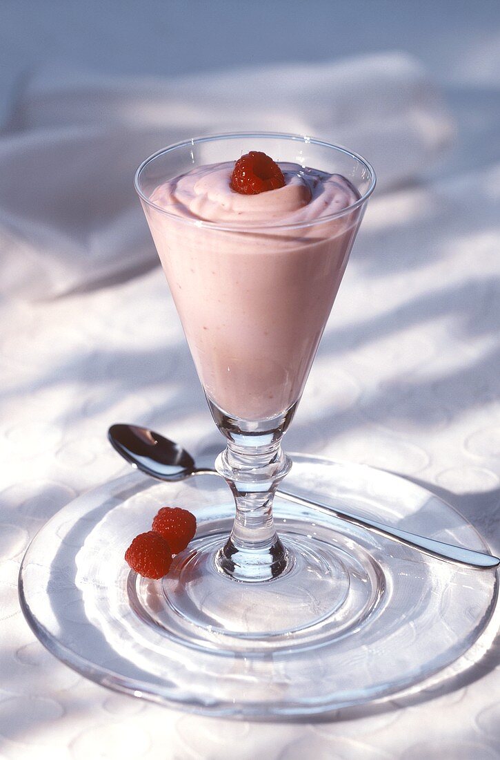 Raspberry mousse decorated with raspberry in a glass