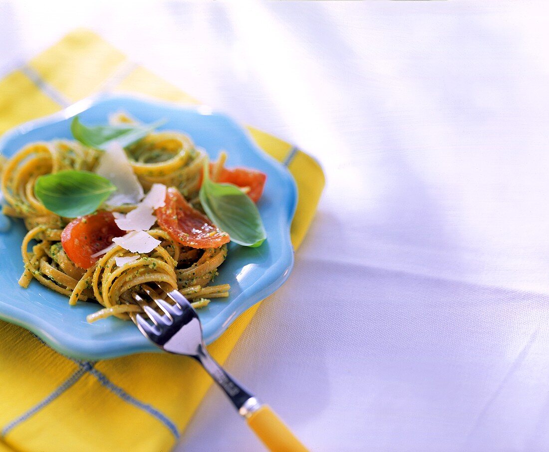 Spaghetti with herb pesto and tomatoes on blue plate