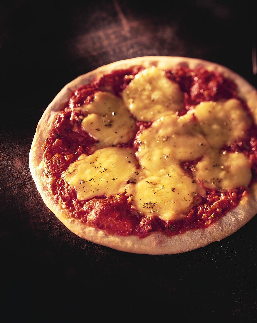 Pizza mit Tomaten und Käse auf dunklem Untergrund