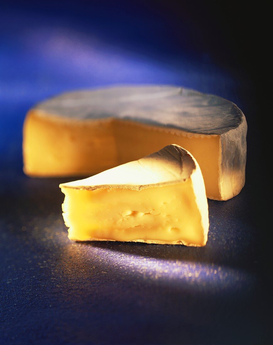 Camembert with a wedge-shaped piece on a blue background