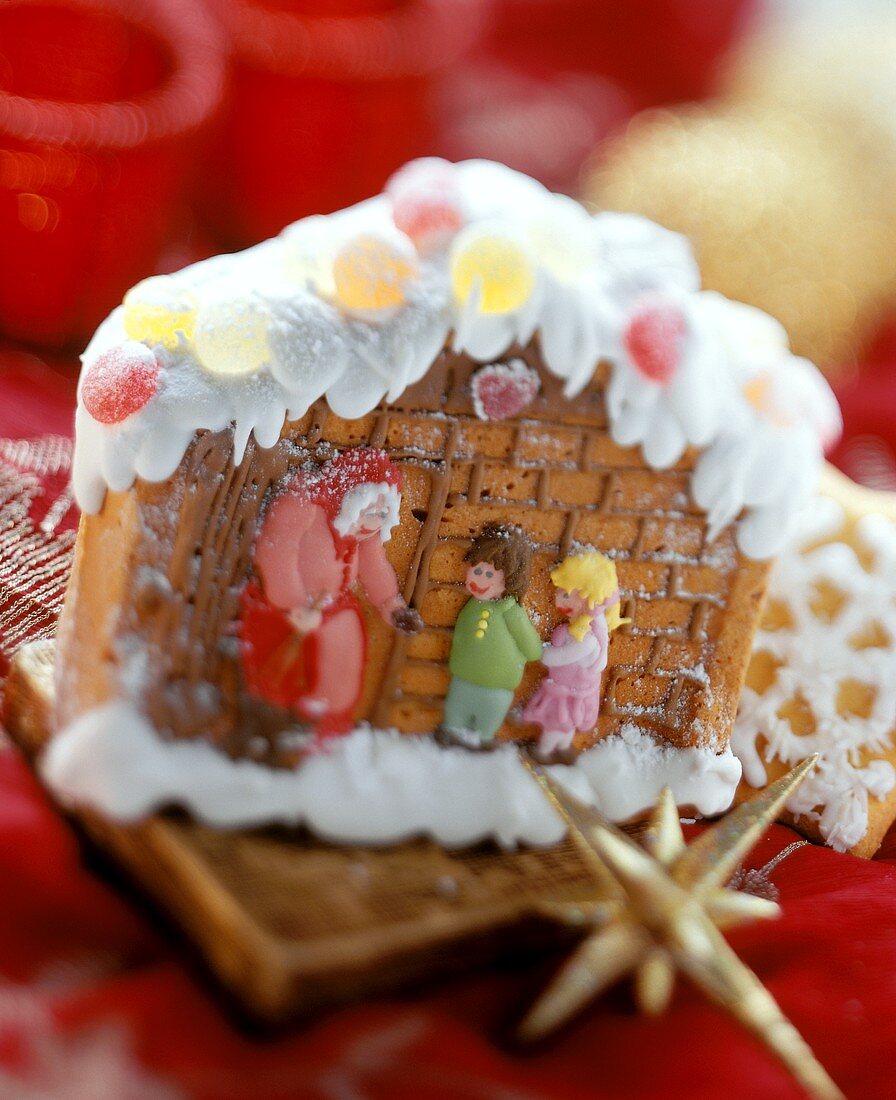 Gingerbread house with fairytale figures on red cloth