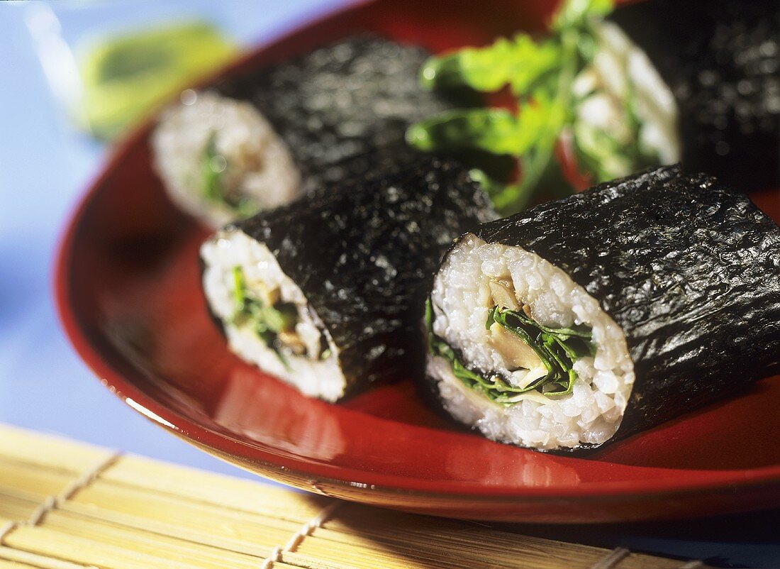 Futo-Maki mit Austernpilzen und Rucola auf rotem Teller