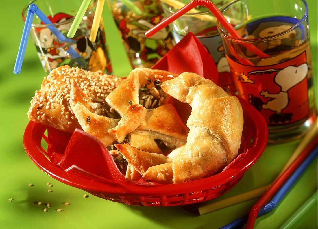 Savoury party food in red bread basket; colourful juice glasses