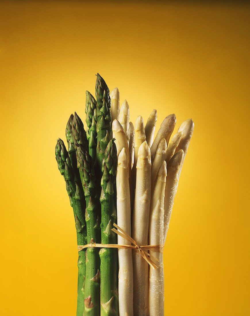 A bunch of white & green asparagus, yellow background