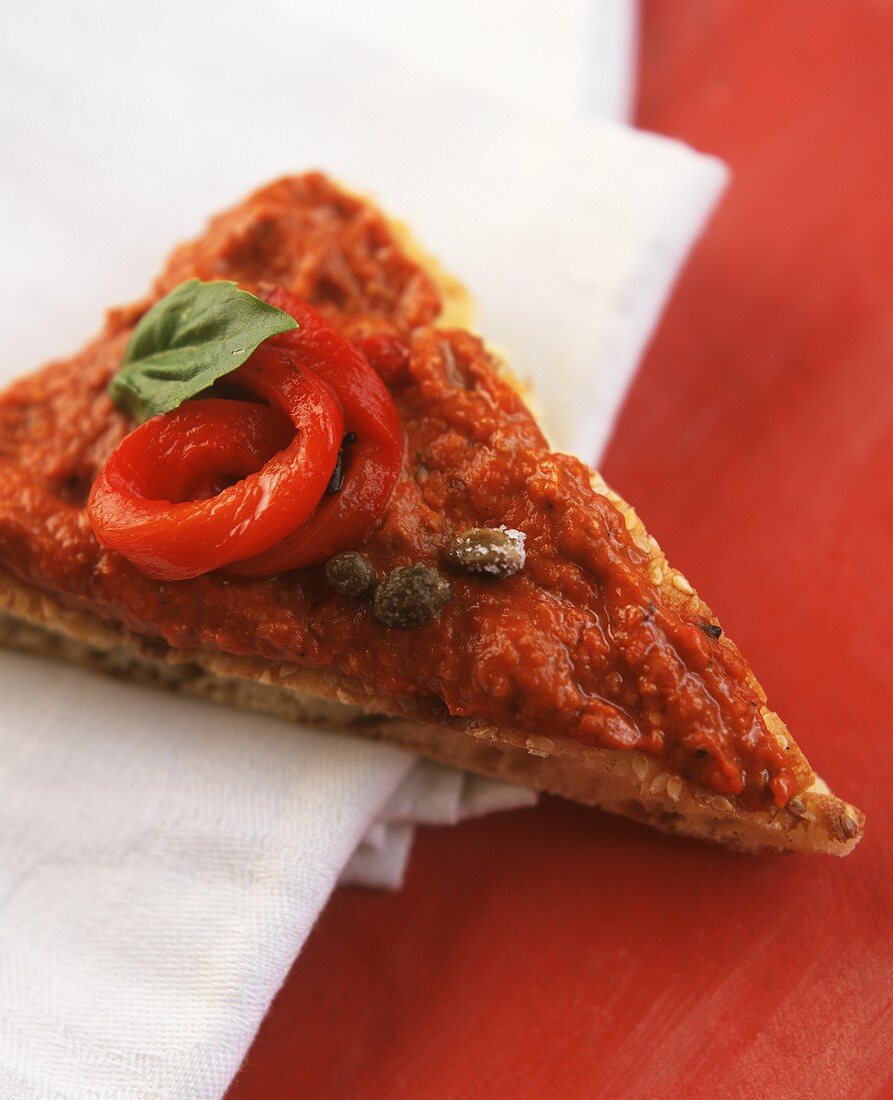 Ein Stück Pizza mit Tomatensauce, Kapern und Paprika