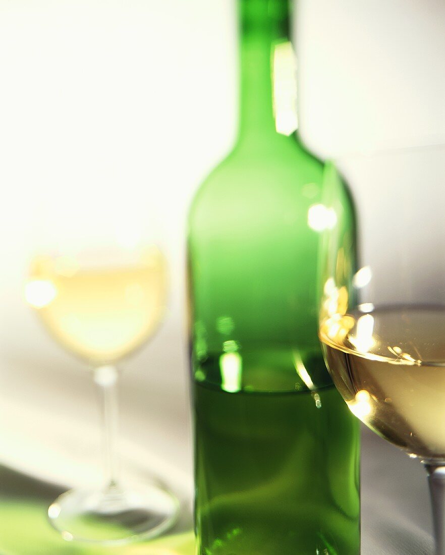 White wine in two glasses and green bottle