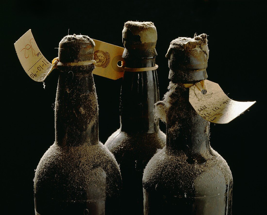 Three old wine bottles with auction labels