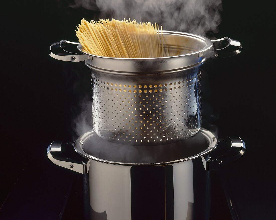 Spaghetti in a pasta pan above steam