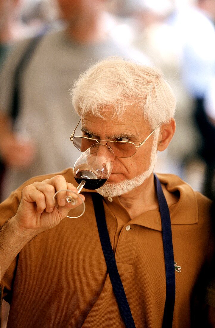 Mann riecht an halb gefülltem Rotweinglas