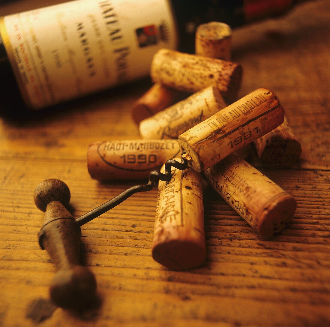 Corks and corkscrews in front of a wine bottle