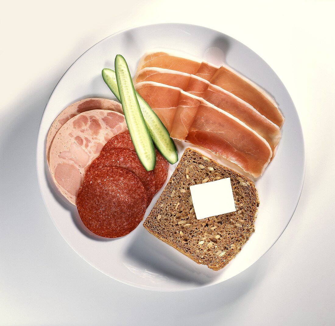 Wholemeal bread, sausage, air-dried ham & cucumber on plate