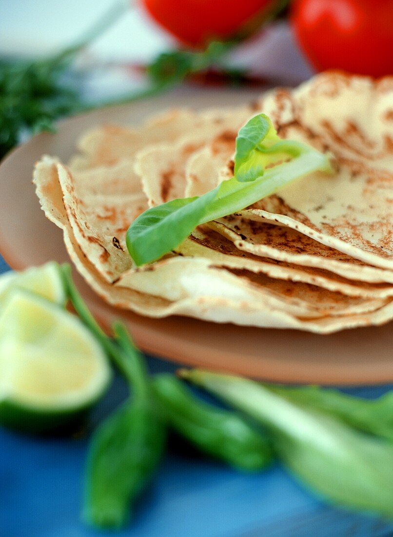 Tortillas in a pile, tomatoes and limes