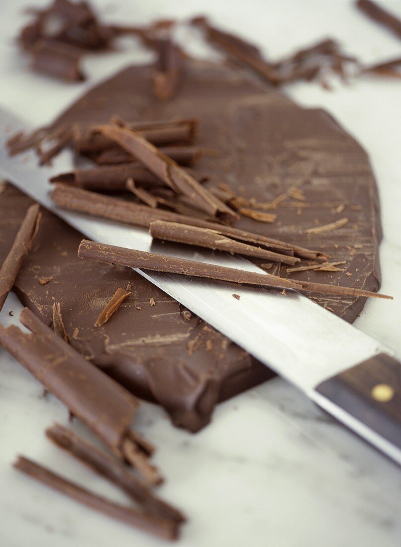 Schokolade und Schokoladenspäne mit Messer auf Marmorplatte