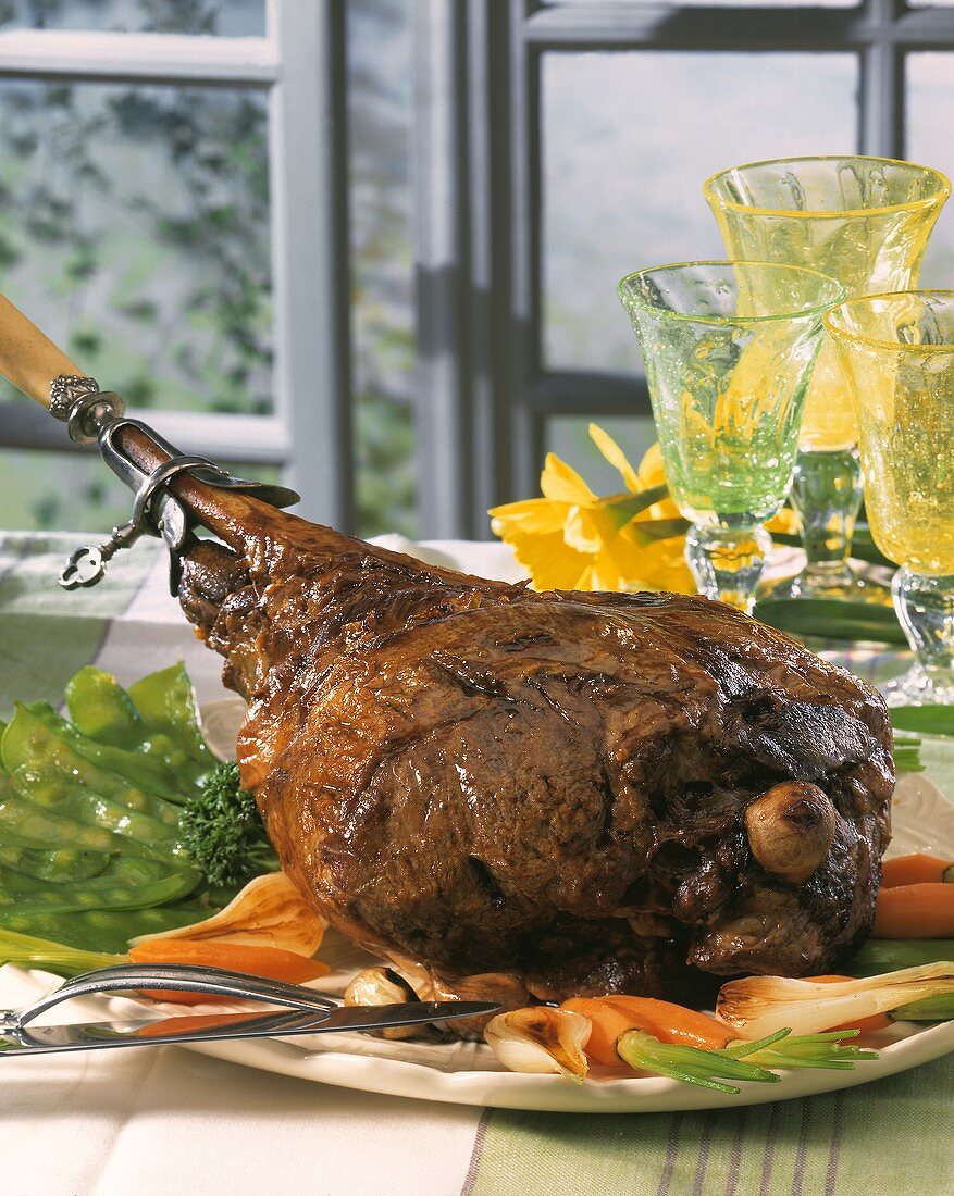 Roast leg of lamb with vegetables on a platter