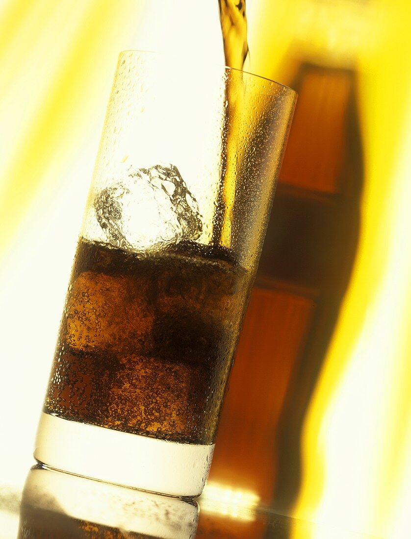 Cola einschenken in Glas mit Eiswürfeln