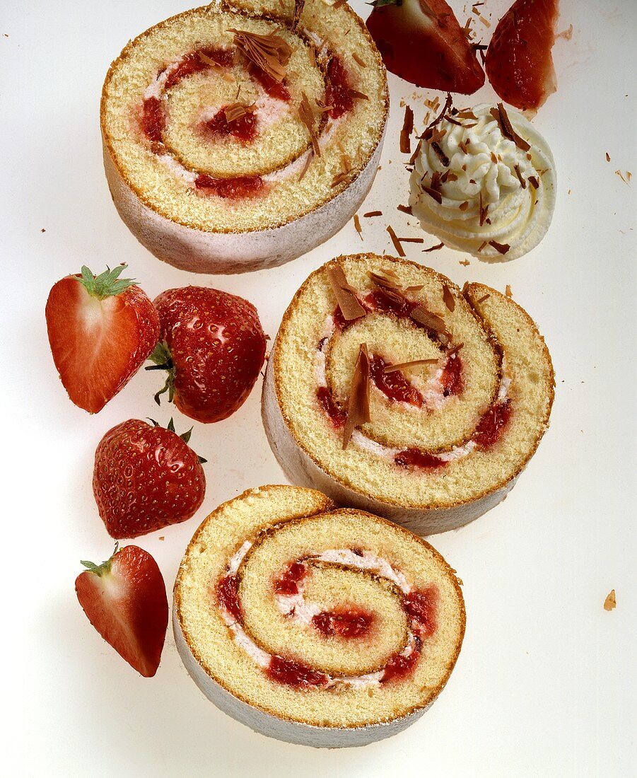 Three slices of strawberry roulade with cream & chocolate curls