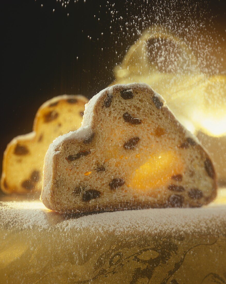Marzipan stollen being sprinkled with icing sugar