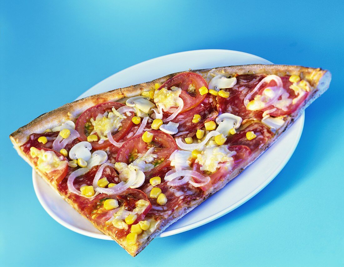 A piece of pizza with sausage, tomatoes, sweetcorn etc