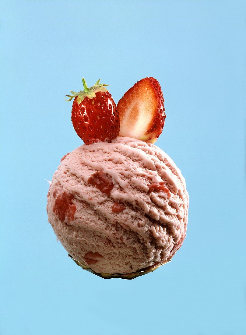 A scoop or strawberry ice cream with strawberry pieces