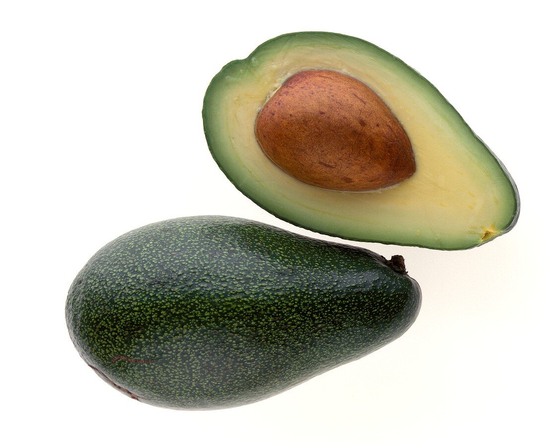 Ganze und halbe Avocado mit Kern