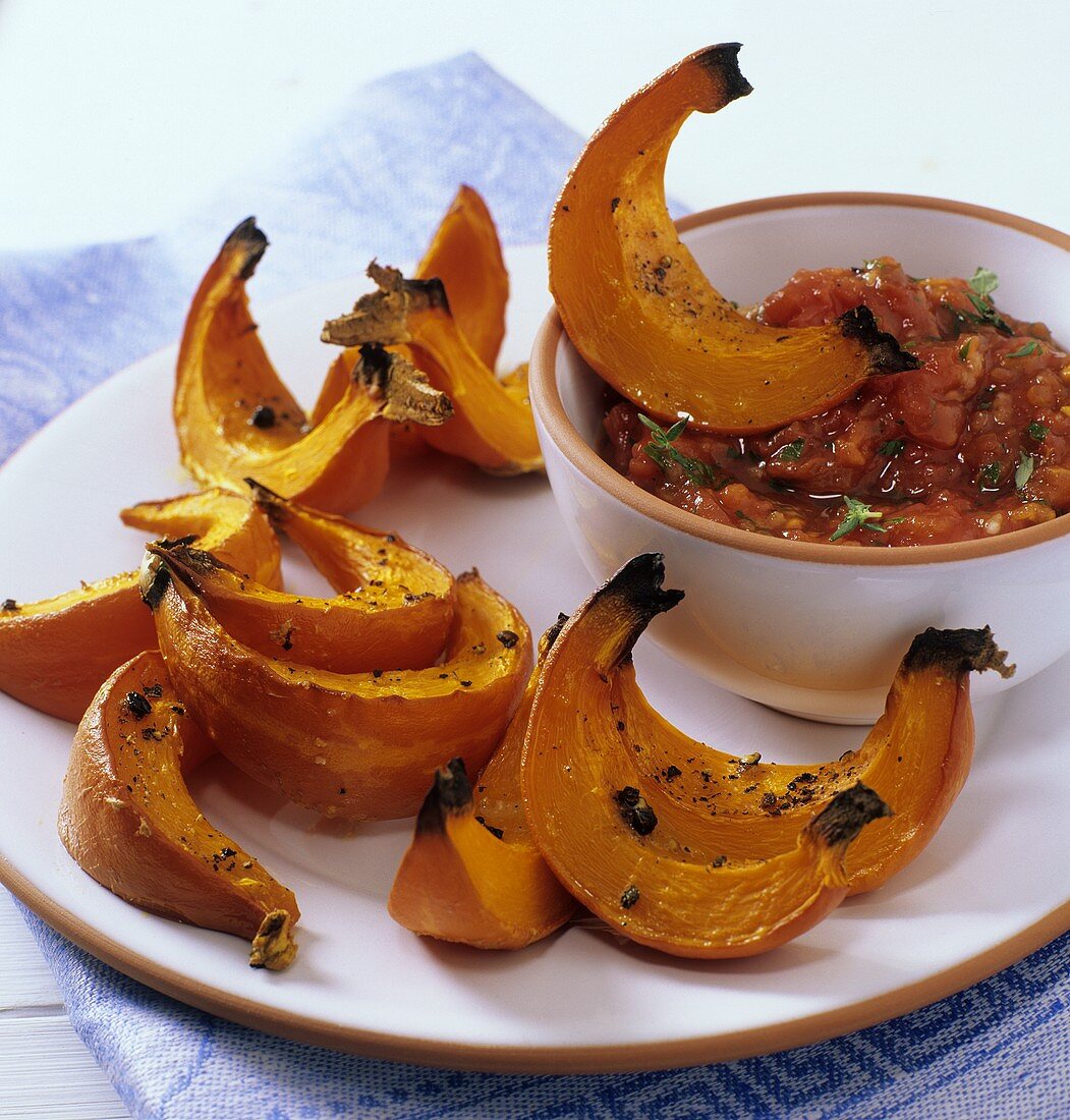 Braised pumpkin wedges with tomato salsa on plate
