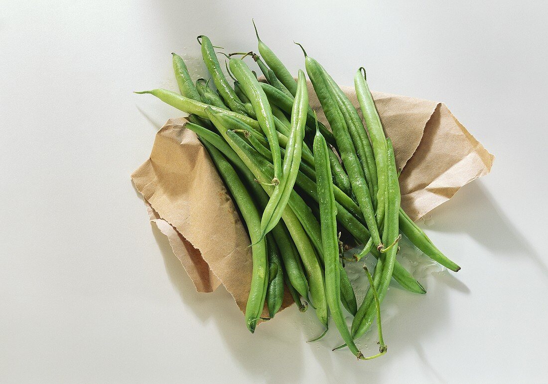 Green French beans on brown paper
