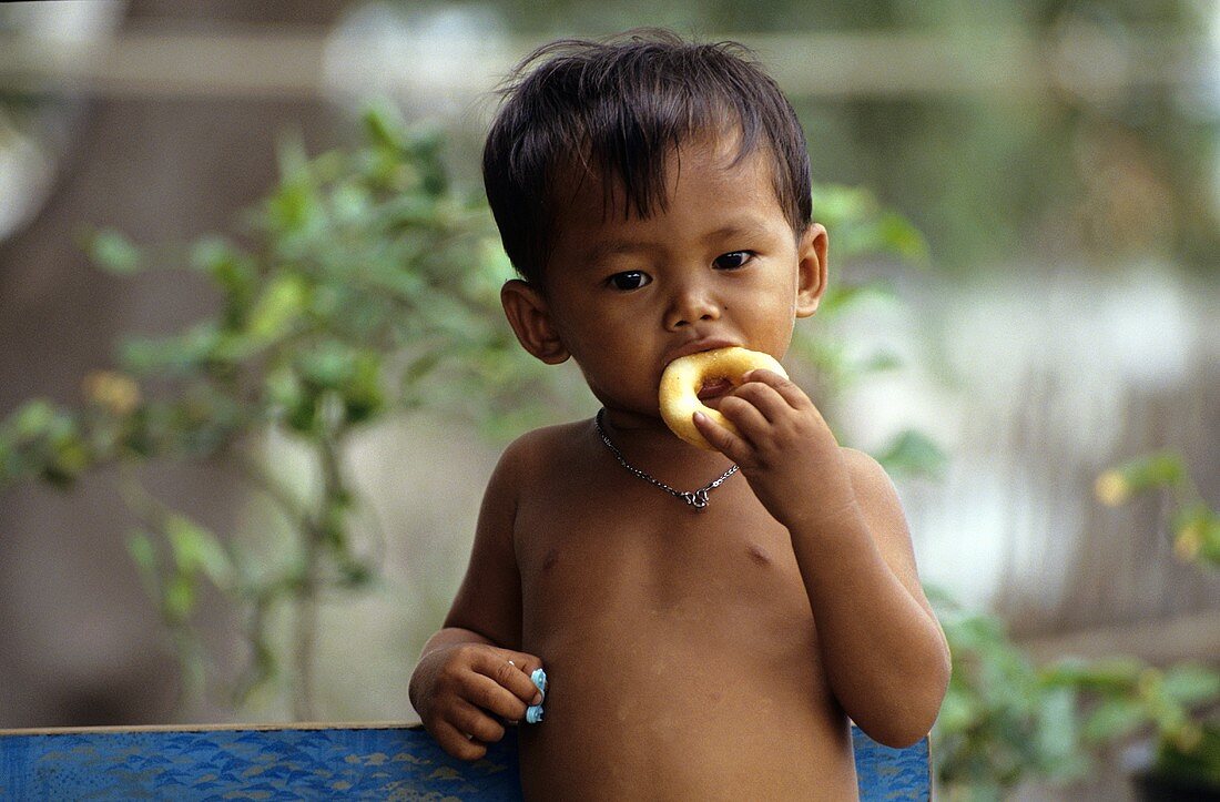 Thailändischer kleiner Junge isst süsses Gebäck