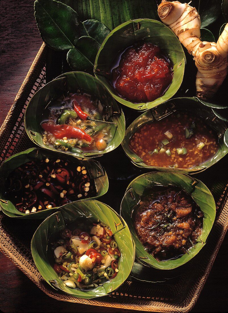 Spicy sauces in banana leaf bowls on tray
