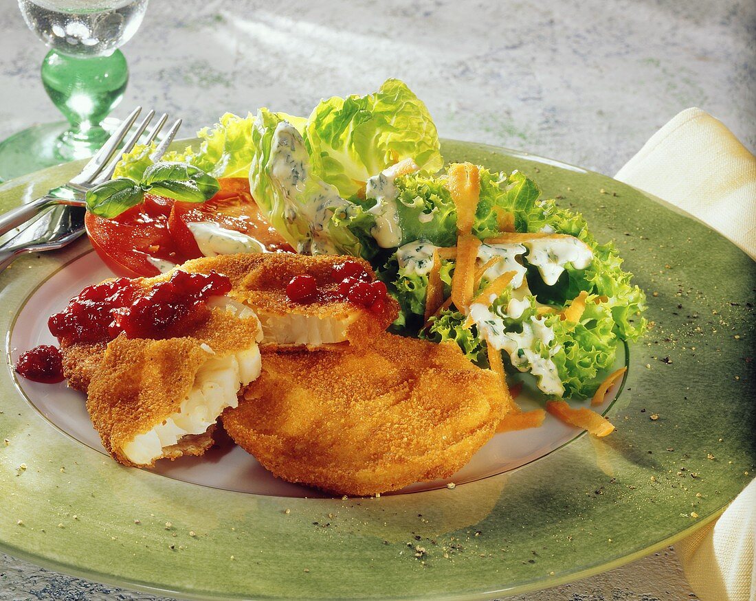 Breaded fish fillet with salad leaves and cranberries