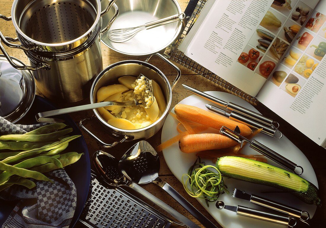 Küchenwerkzeuge für die Gemüseküche; aufgeschlagenes Kochbuch