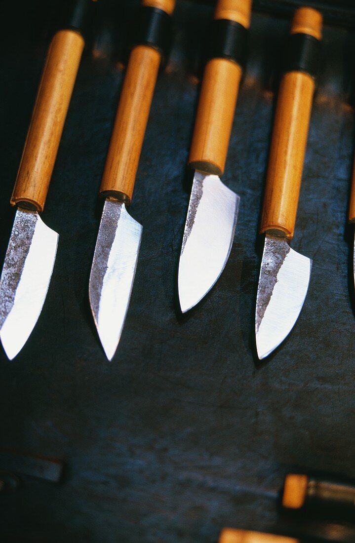 Vier verschiedene scharfe Messer auf schwarzem Untergrund