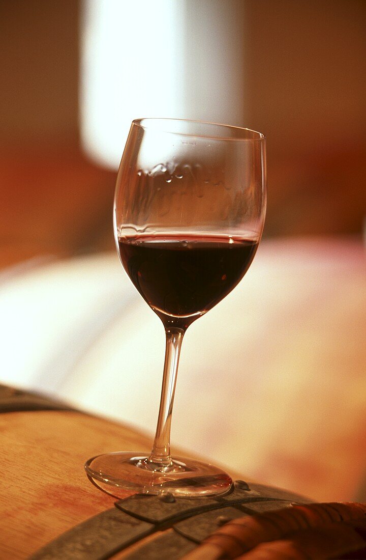 Ein Glas Rotwein auf einem Fass