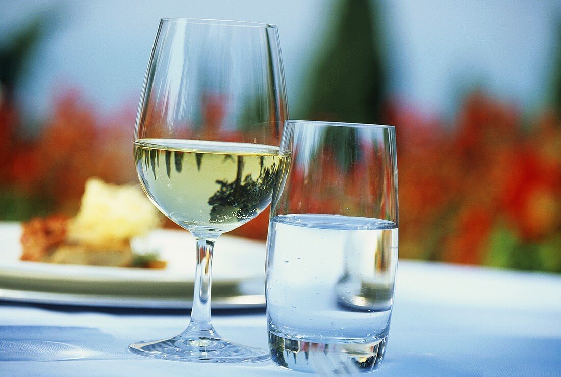 White wine glass and water glass on table in the open air