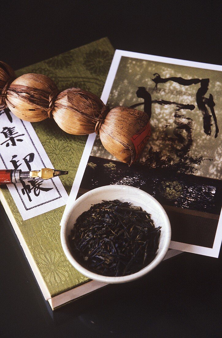 Asiatisches Teestilleben mit Teezopf, Teeblättern etc.