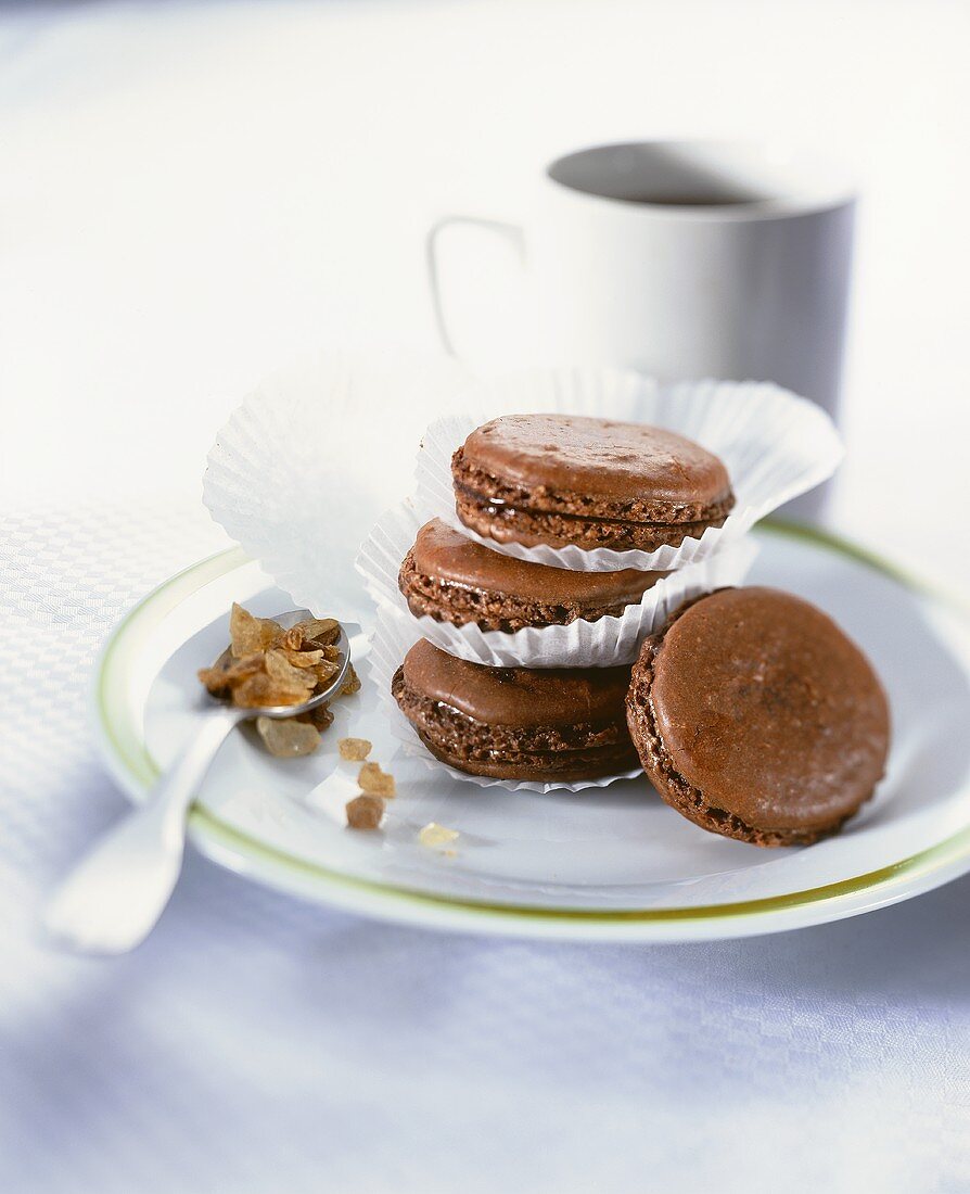 Chocolate macaroons in paper cases on plate; coffee