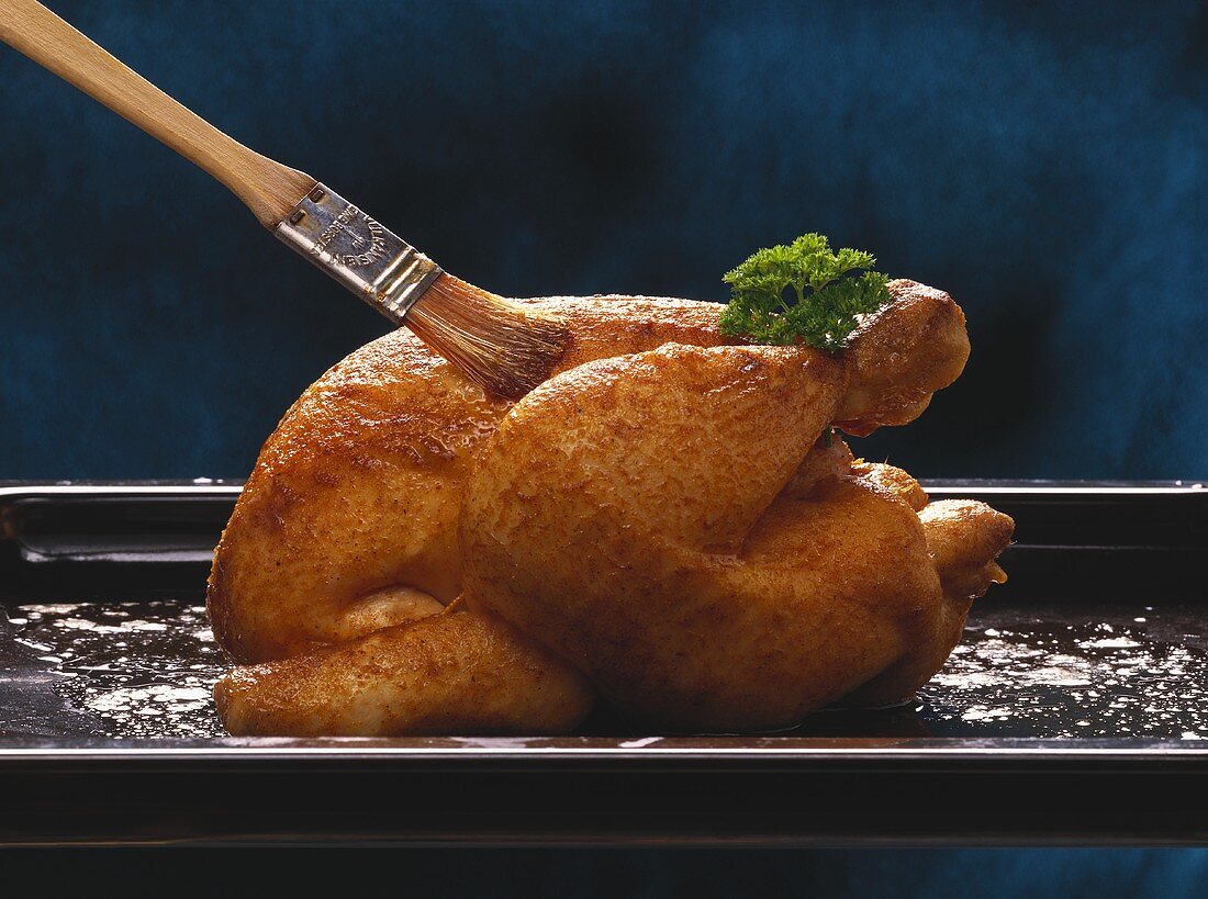 Basting roast chicken with a basting brush
