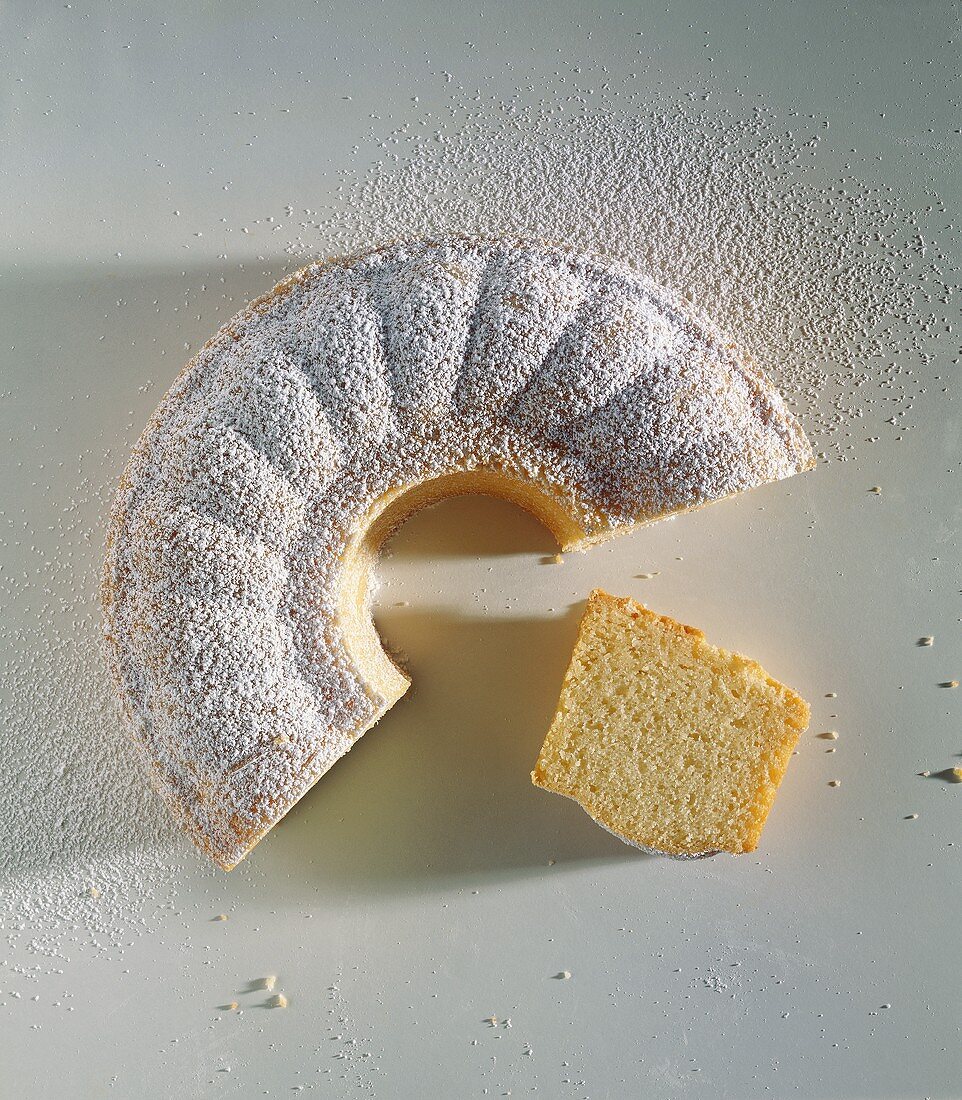 Sandkuchen mit Puderzucker und einzelnem Kuchenstück
