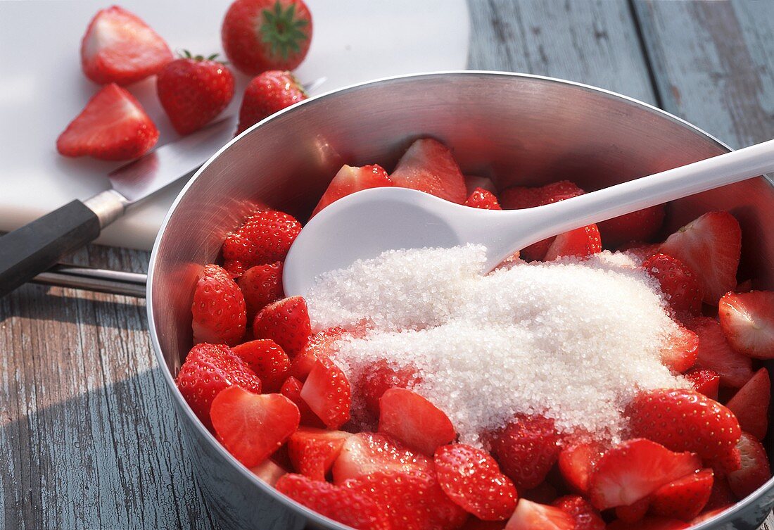Making strawberry jam; stirring strawberries and sugar