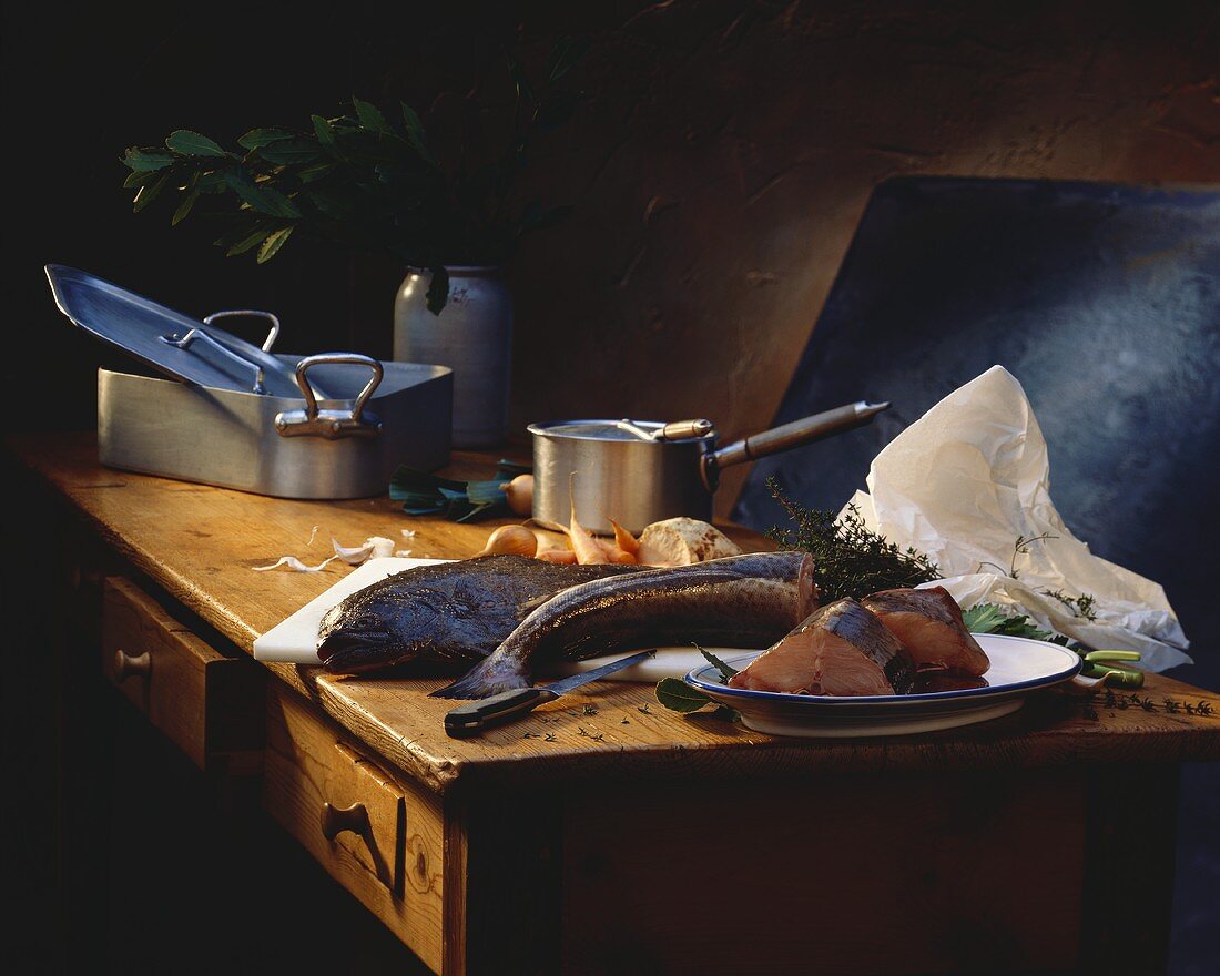Fresh halibut on wooden table; saucepans; vegetables; herbs