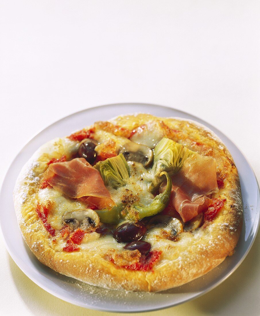 Pizza with ham, artichokes and olives on plate