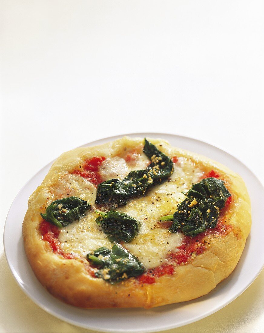 Pizza with cheese and spinach on plate