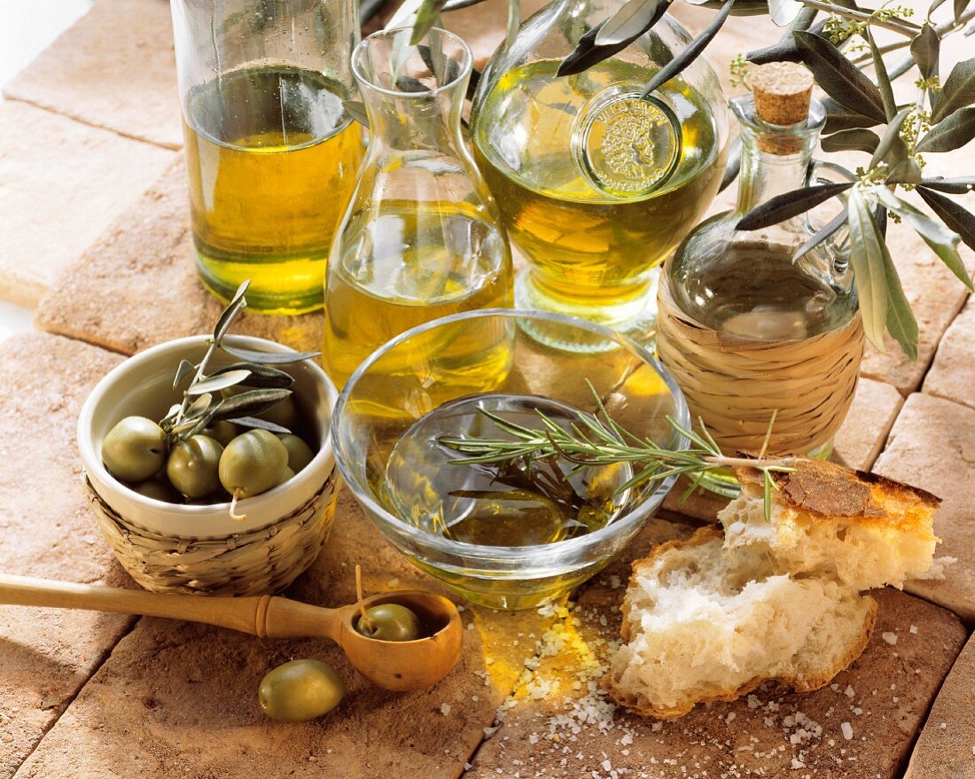 Stillleben mit Olivenöl, grünen Oliven und Weißbrot