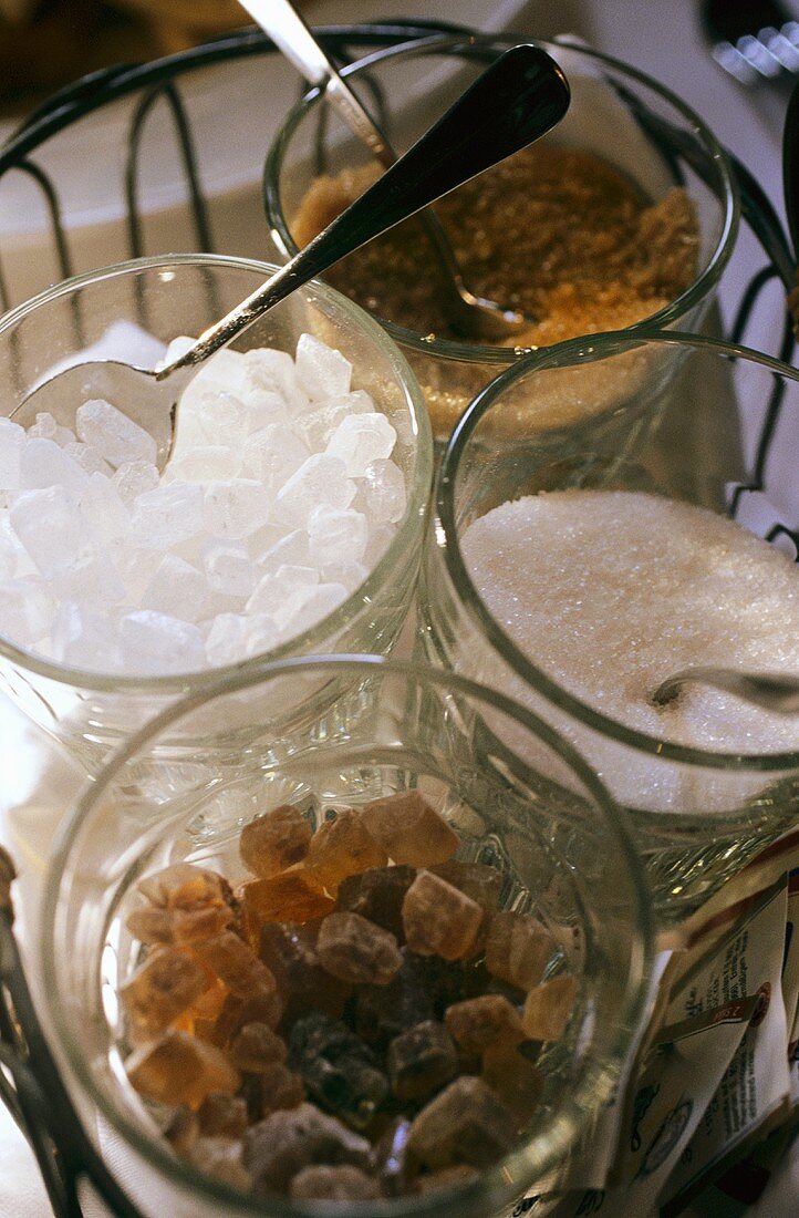 Weisser und brauner Zucker sowie Kandiszucker in Glasschalen