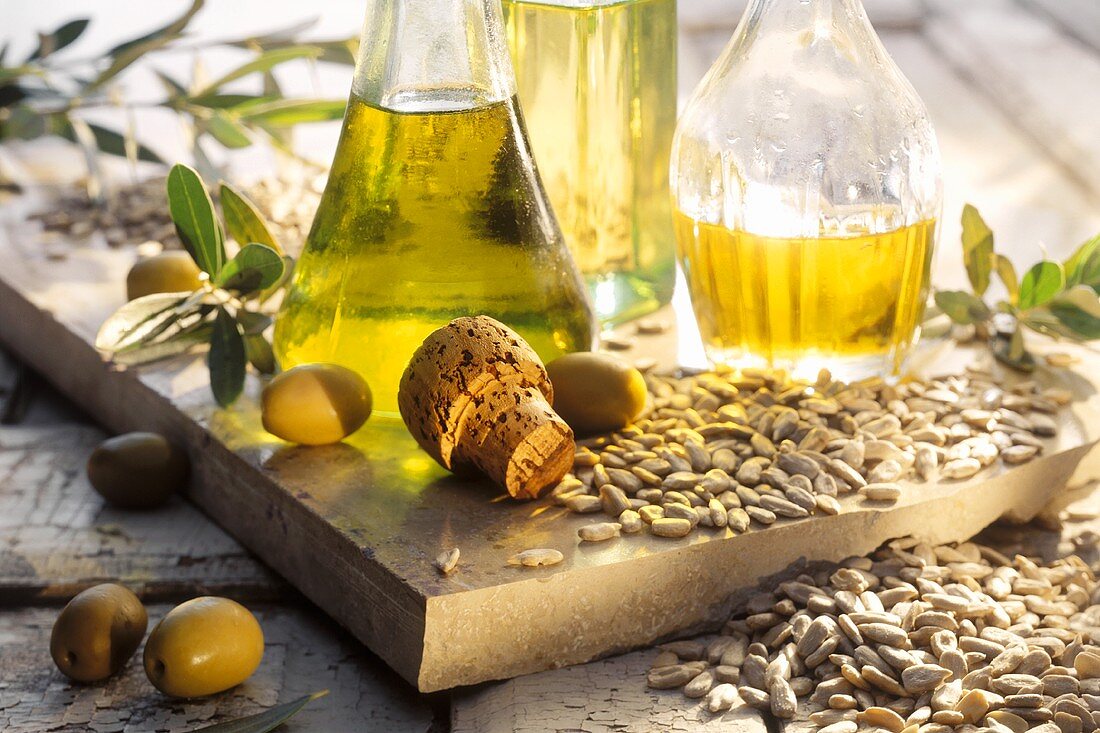 Verschiedene Öle in Karaffen; Oliven; Sonnenblumenkerne