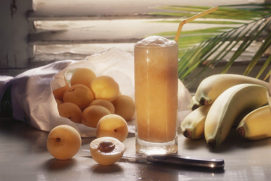 Aprikosen-Bananen-Drink, umgeben von frischen Früchten