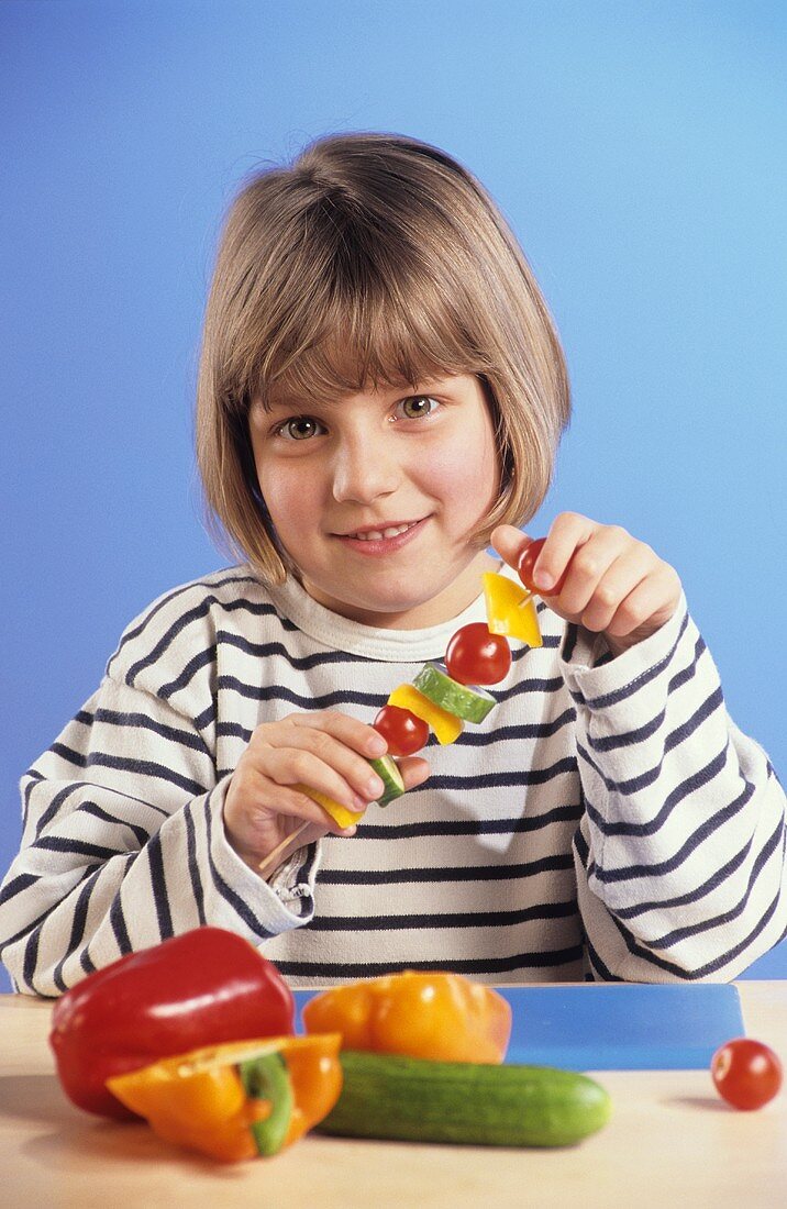 Small girl threading vegetables on skewer