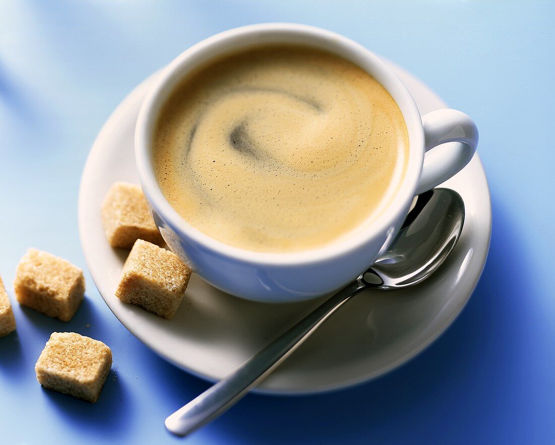 A cup of caffe crema and raw sugar cube