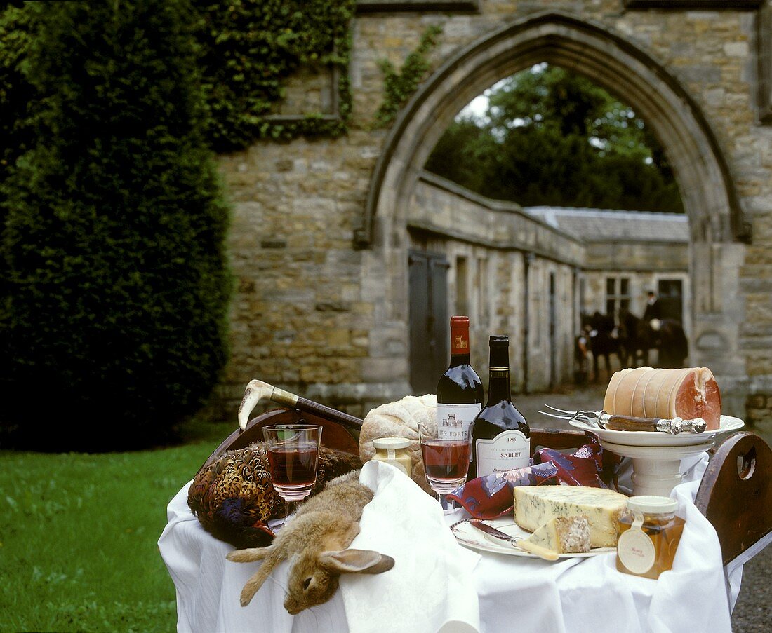 Buffet mit Käse, Wein und Wild vor Burgmauer und Reitern